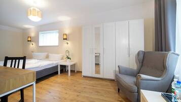 Quarto moderno com cama, mesa de cabeceira, abajur, guarda-roupa e uma poltrona cinza.