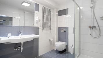 A modern bathroom with a glass shower enclosure, a white sink, and a toilet.