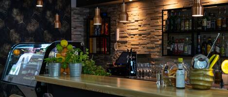 A bar area with a counter, potted plants, and a selection of bottles and glasses.
