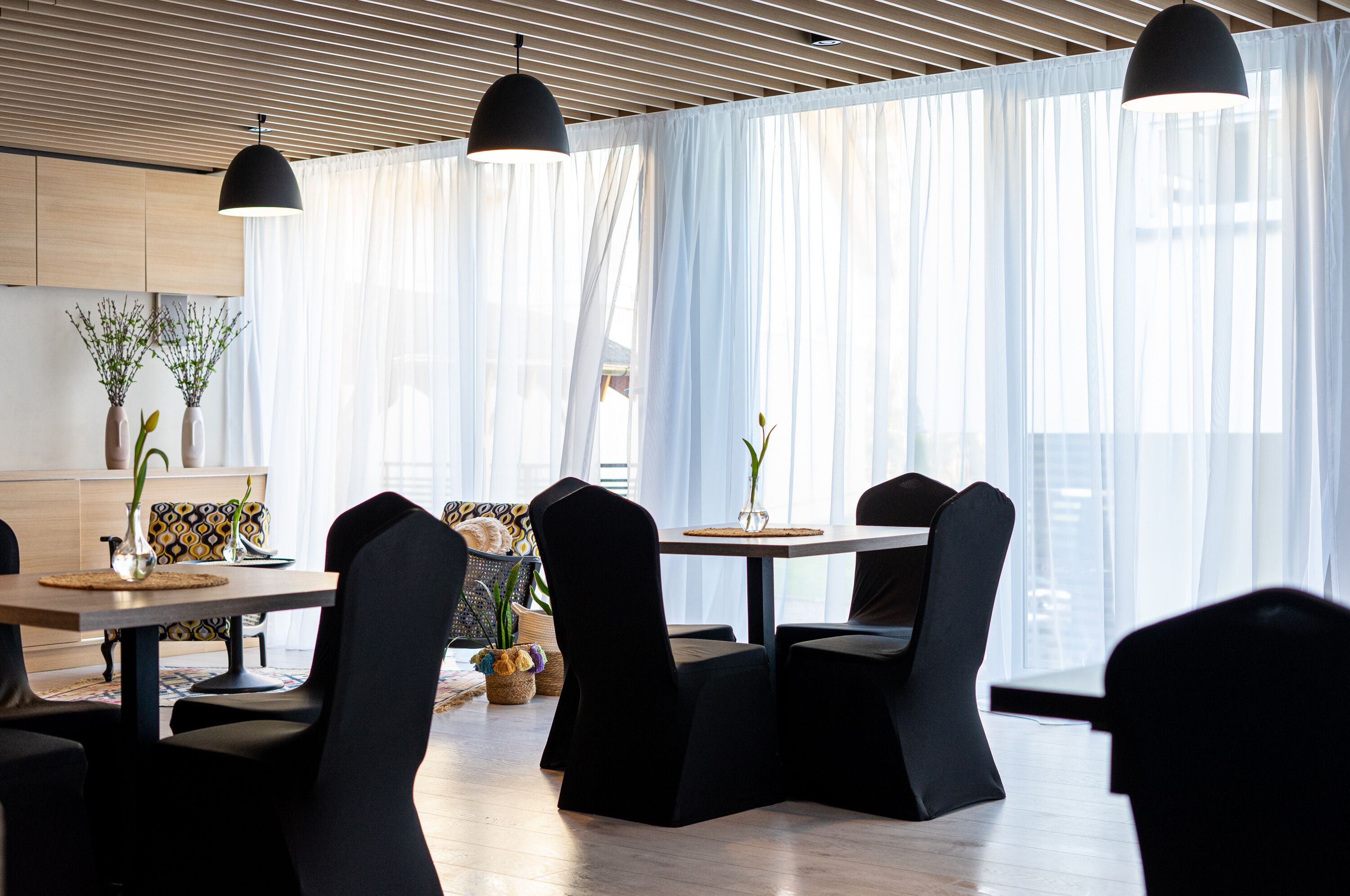 A modern dining area with black upholstered chairs, a wooden table, and pendant lighting.