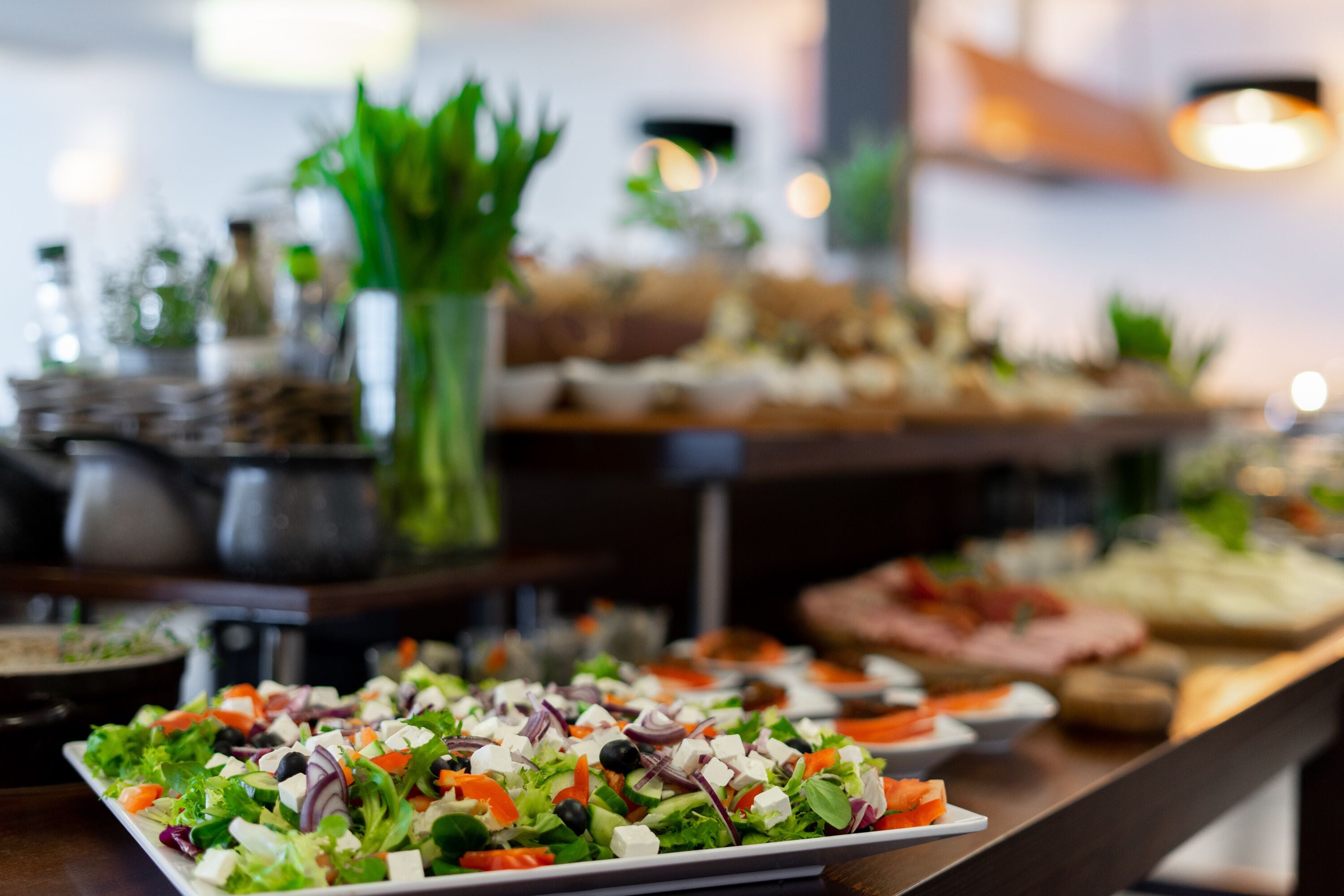 Un buffet proposant divers plats, notamment une salade composée de différentes variétés de laitues, de tomates et de fromage.