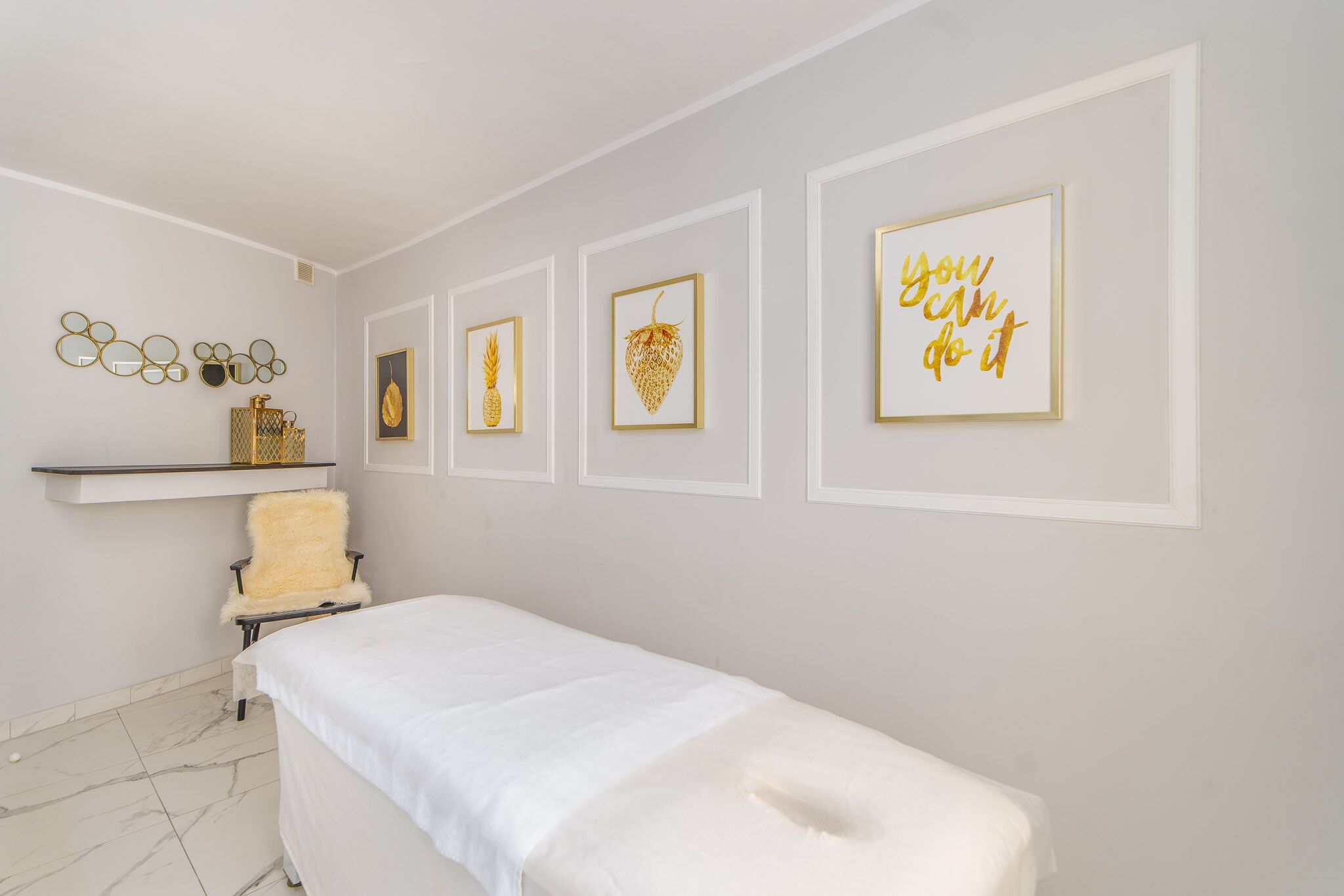 A room with a bed, a chair, and wall art including a pineapple and a motivational quote.
