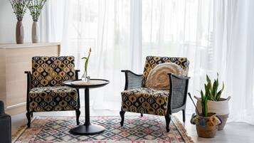 A room with two patterned armchairs, a small round table, and a potted plant.