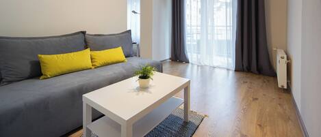 A modern living room with a grey sofa, a white coffee table, and a potted plant.