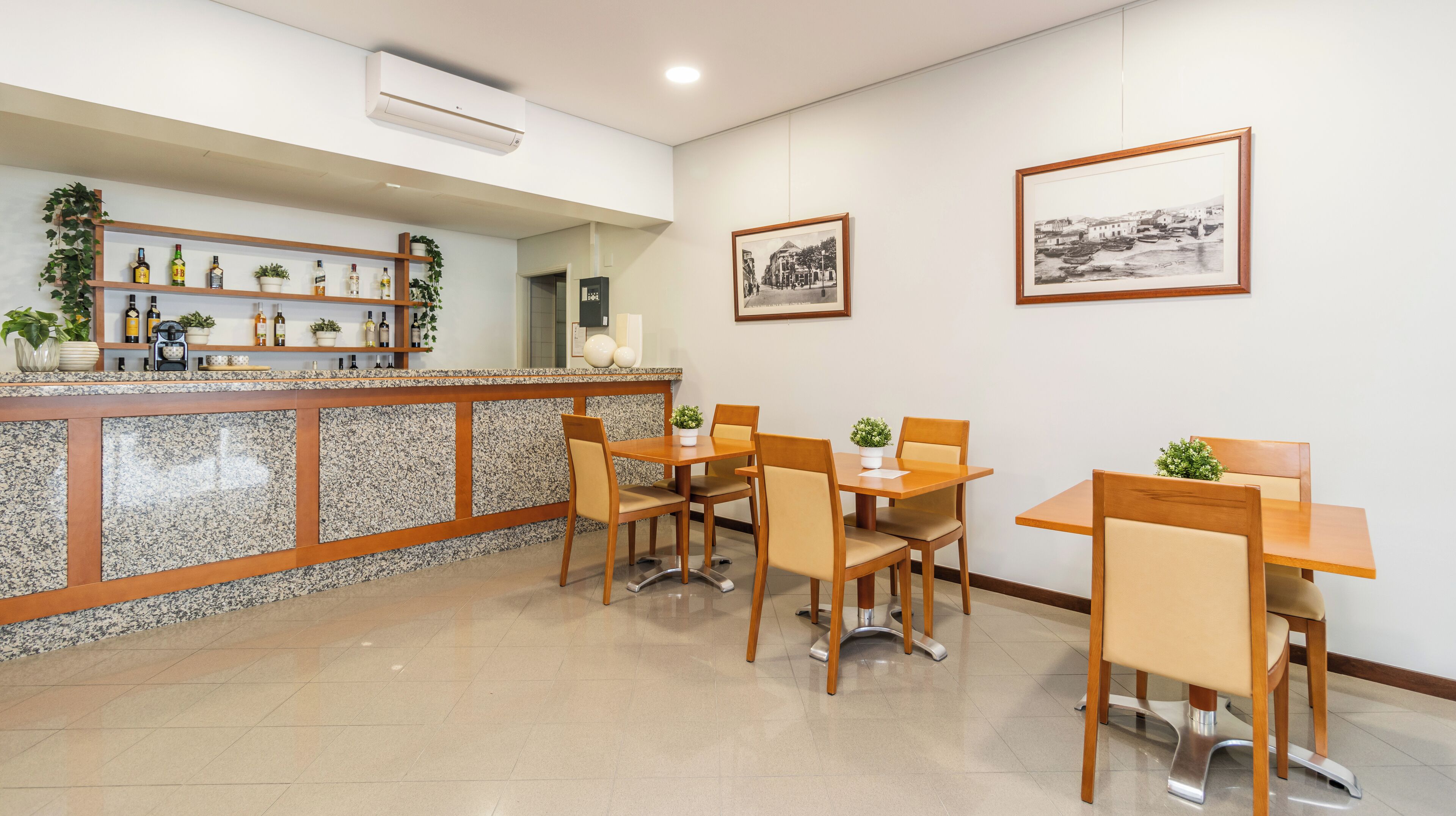 A restaurant with a counter, chairs, and two framed pictures on the wall.