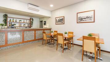 A restaurant with a counter, chairs, and two framed pictures on the wall.
