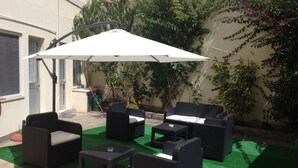 An outdoor patio area with wicker furniture, including sofas and tables, under a large umbrella. - Hotel Dona Leonor (Caldas da Rainha)