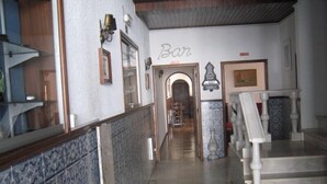 A hallway with a tiled floor, a staircase with white balusters, and a wall with a 'Bar' sign. - Hotel Dona Leonor (Caldas da Rainha)