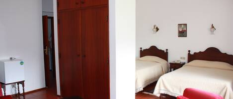 A room with two beds, a wooden wardrobe, a small table, and a red chair.