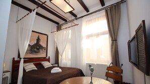A hotel room with a bed, a round wooden table, a TV, and a painting on the wall. - Pension Noemi (Brasov)