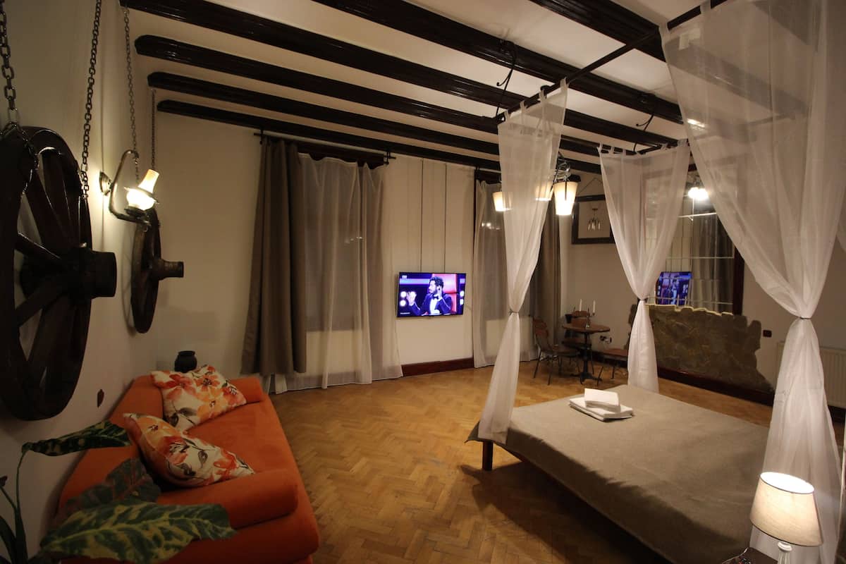 Quarto com cama, sofá, televisão e mesa.