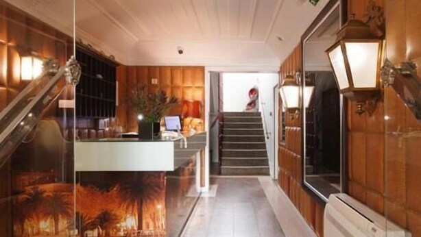 A hotel lobby with a wooden interior, a reception desk, a staircase, and a large window with a view. - Hotel João Padeiro (Aveiro)