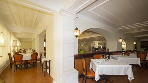 A restaurant with white tables and chairs, wooden floors, and a classic interior design. - Hotel João Padeiro (Aveiro)