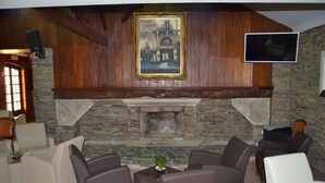 A cozy lounge area with stone walls, a fireplace, and comfortable seating. - Hotel João Padeiro (Aveiro)