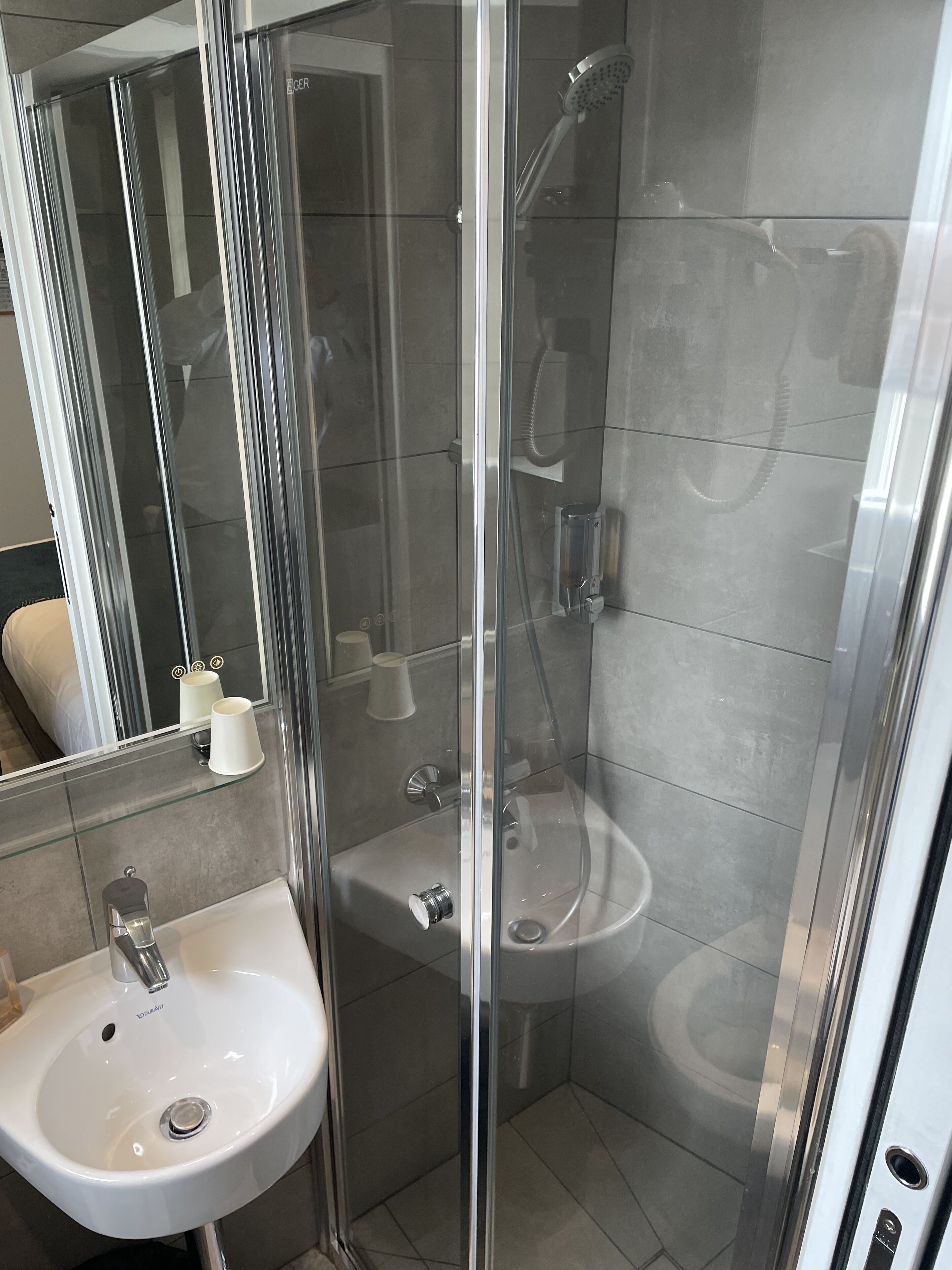 A modern bathroom with a glass-enclosed shower, a white sink, and a mirror.