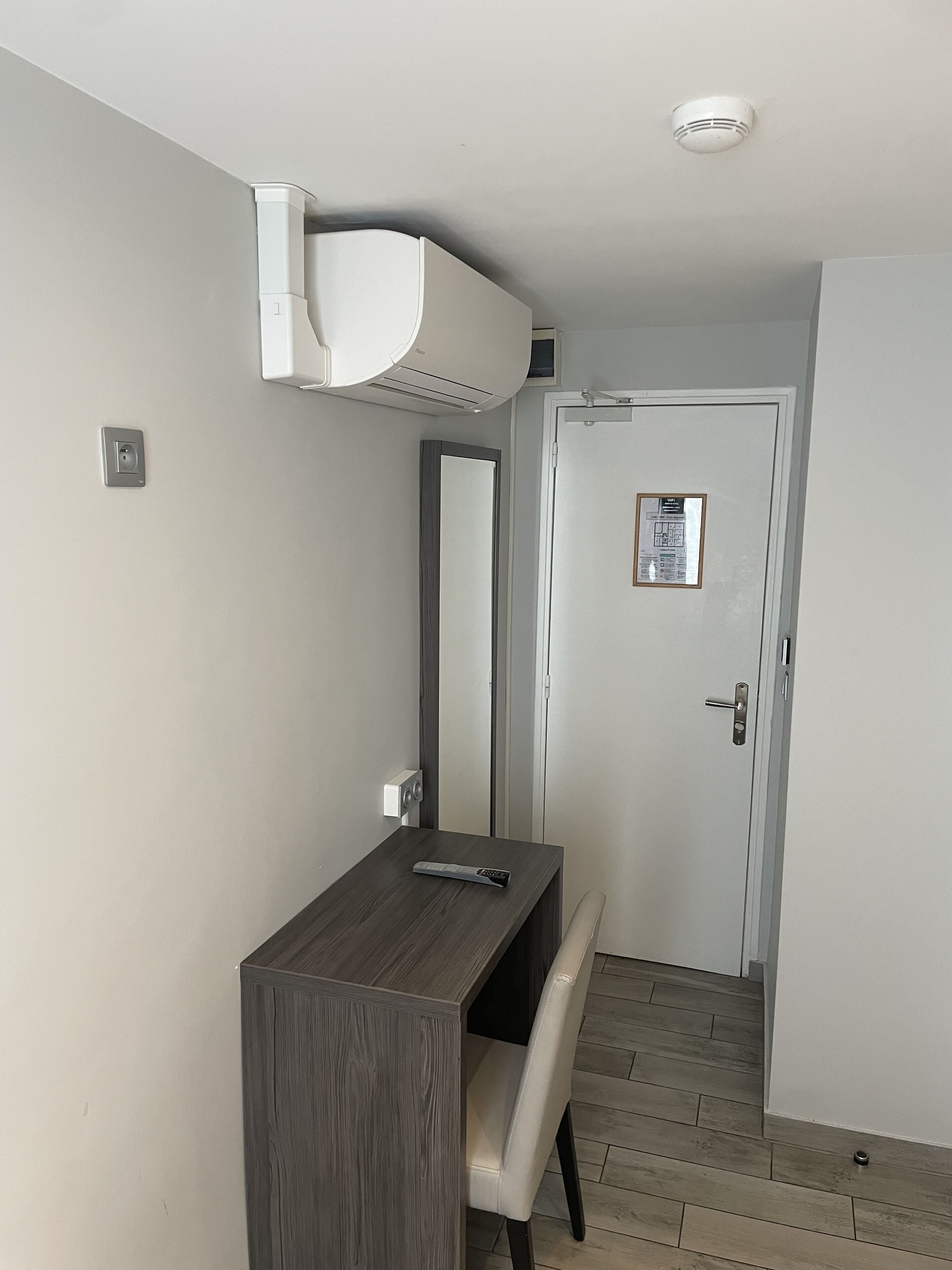 Ein modernes Badezimmer mit einem Holz-Waschtisch, einem Spiegel, einer Toilette und einer unter der Decke angebrachten Klimaanlage.