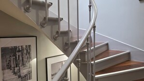 A staircase with a white railing, wooden steps, and black-and-white framed pictures on the walls. - Mary's Hotel République (Paris)