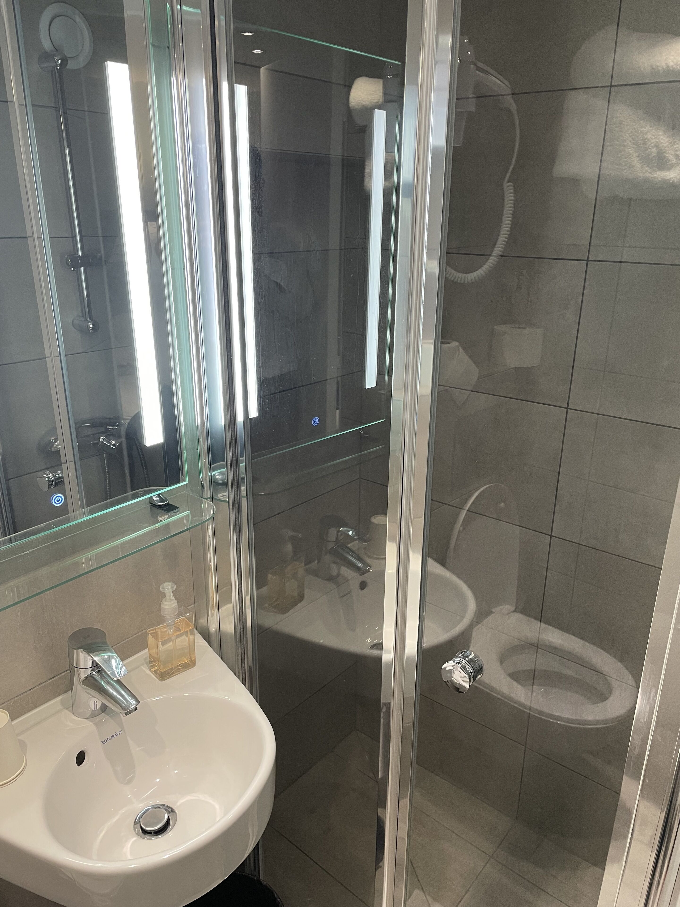 A modern bathroom with a glass-enclosed shower, a white sink, and a toilet.