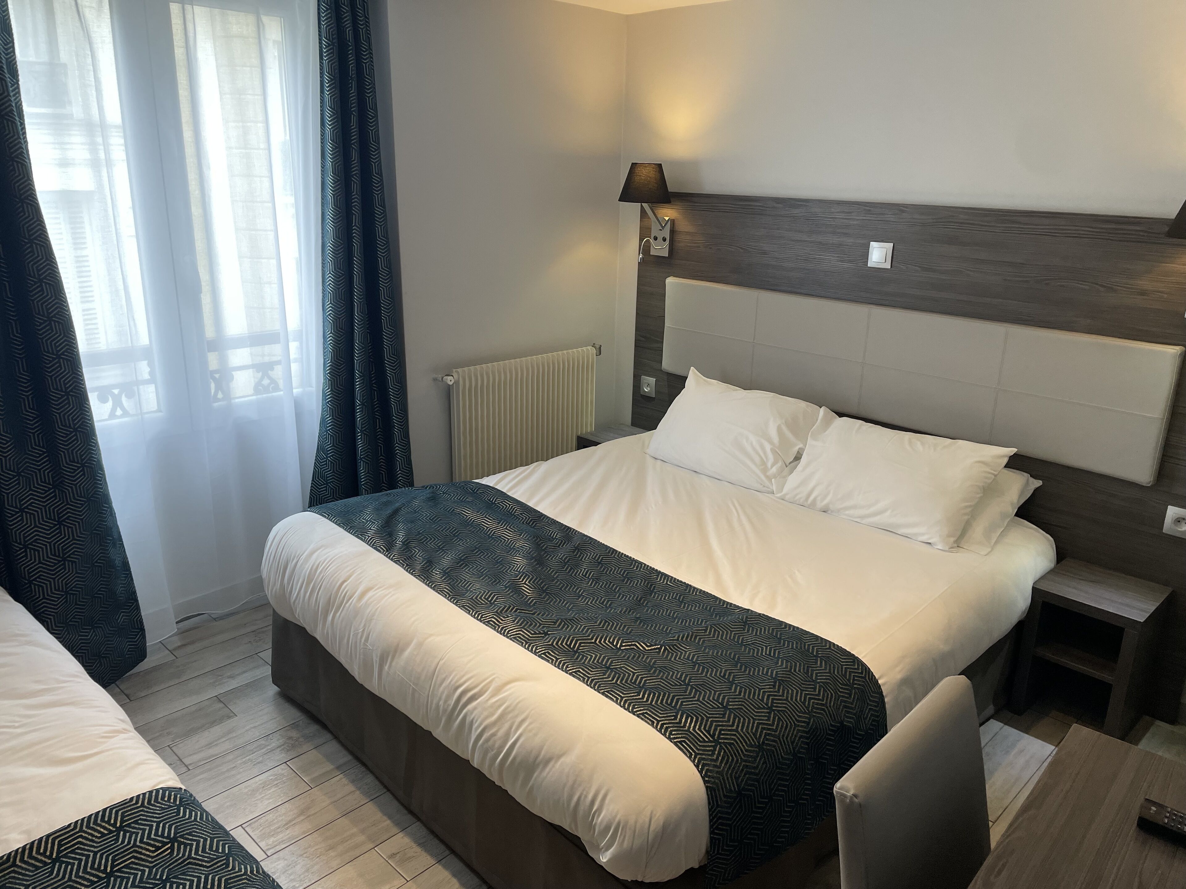 Habitación de hotel moderna con una cama grande, una mesita de noche y una lámpara.