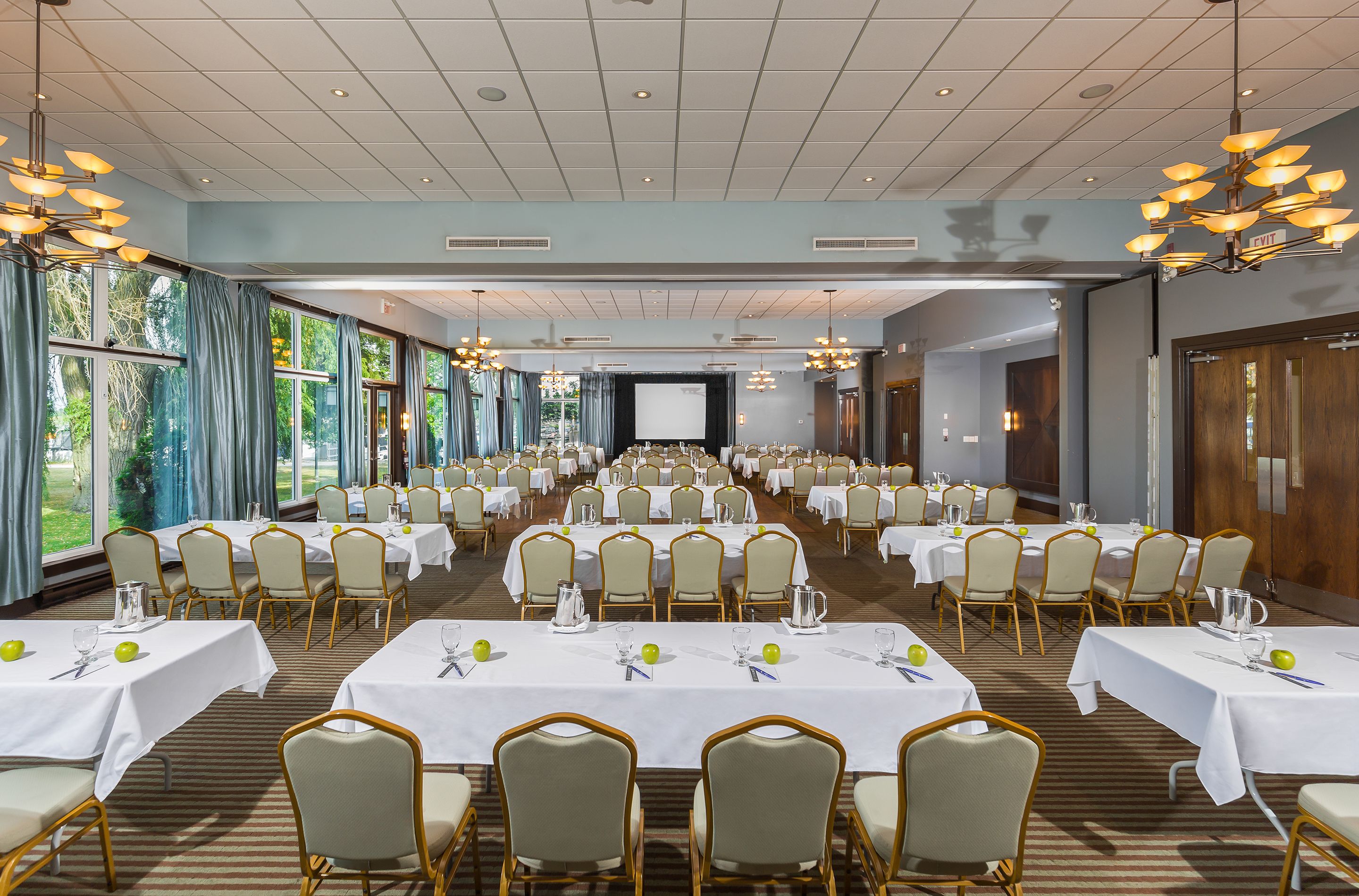 Un amplio salón de banquetes con numerosas mesas y sillas, dispuesto para eventos.