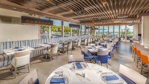 Um restaurante moderno com assentos listrados, janelas amplas e vista para a cidade.