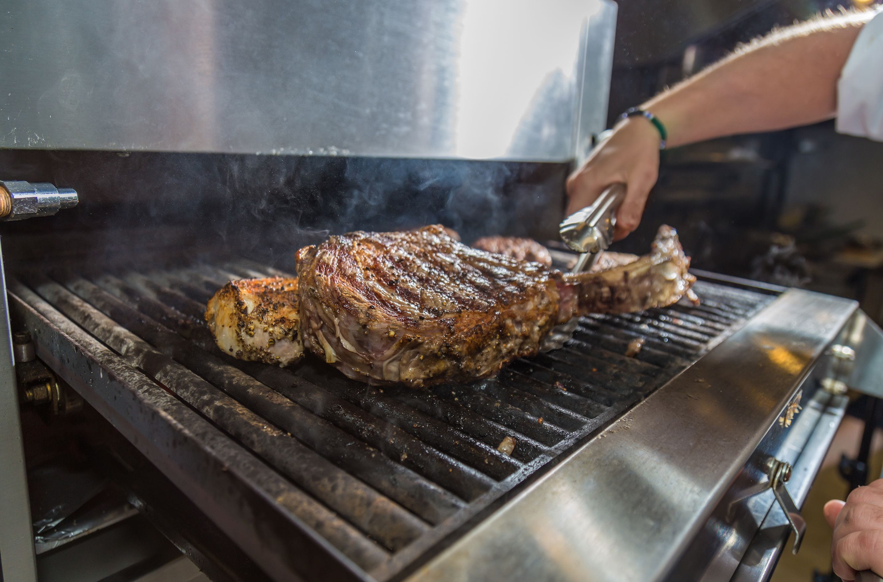 Una parrilla grande con un bistec en cocción.