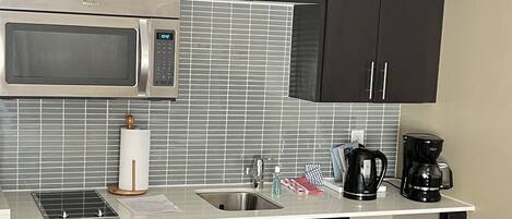 A compact kitchen with a microwave, sink, and coffee maker.