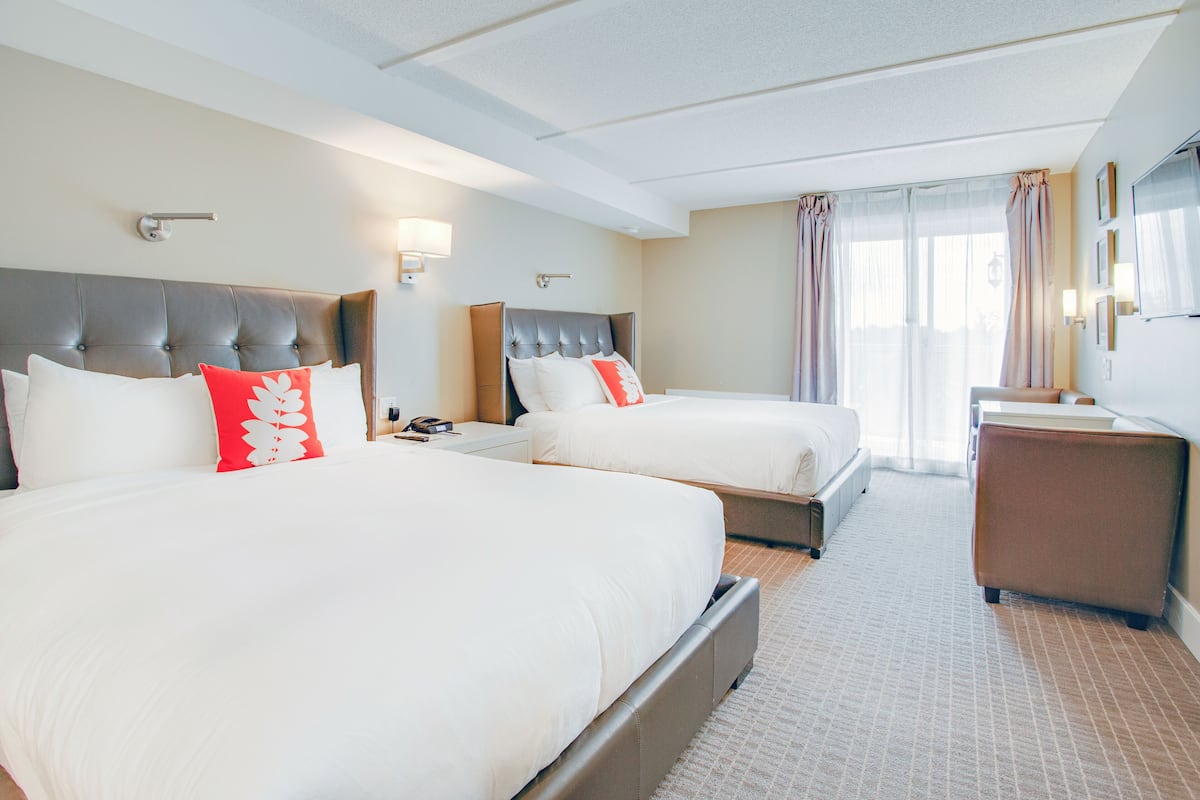 A hotel room with two beds, a desk, and a chair.