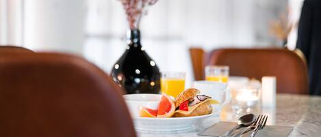 A breakfast setting with a plate of food, a glass of orange juice, and a vase with dried flowers.