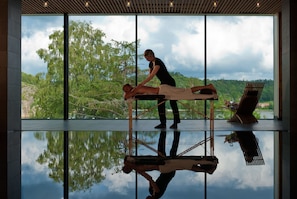 Sessão de massagem em um espaço com grandes janelas e vista para paisagem natural.