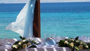 Ein Tisch ist für eine Hochzeit gedeckt, mit Blick auf das Meer.