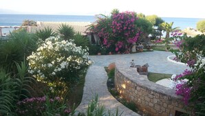 Ein Garten mit einem Kiesweg, verschiedenen Pflanzen und Blick auf das Meer.