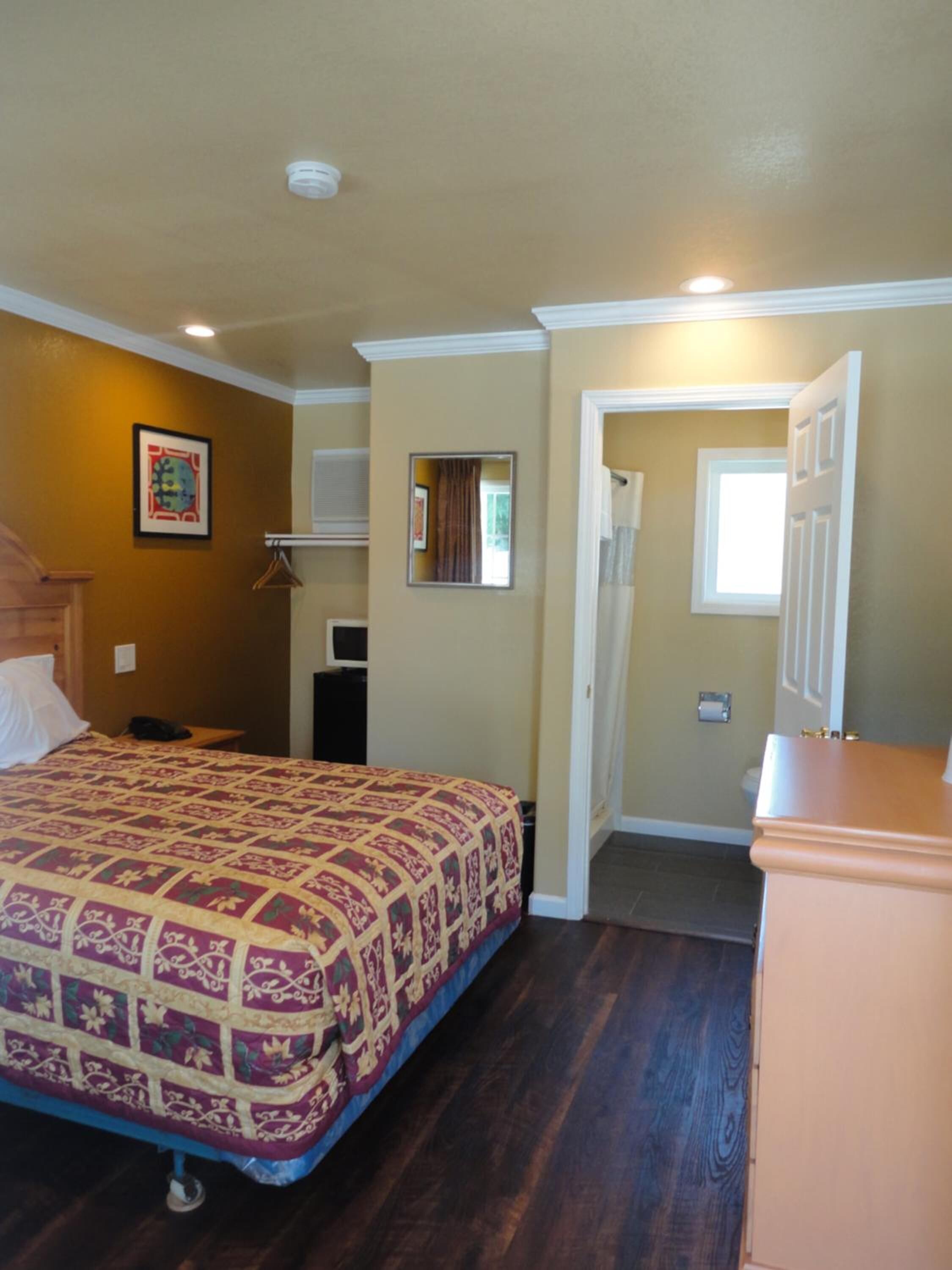 Un dormitorio con cama, cómoda, espejo y puerta que da a otra habitación.