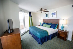A hotel room with a bed, a desk, a ceiling fan, and a window. - Atlantic Terrace (Daytona Beach Shores)