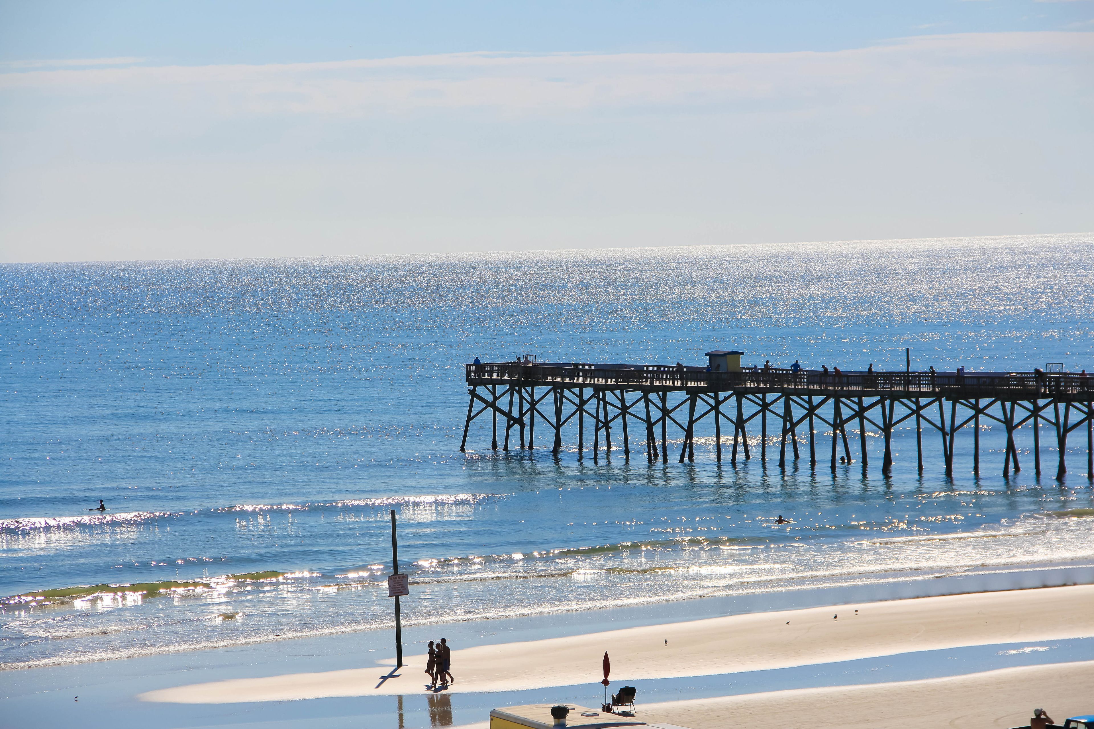 A pier extending into the ocean with a beach in the foreground.