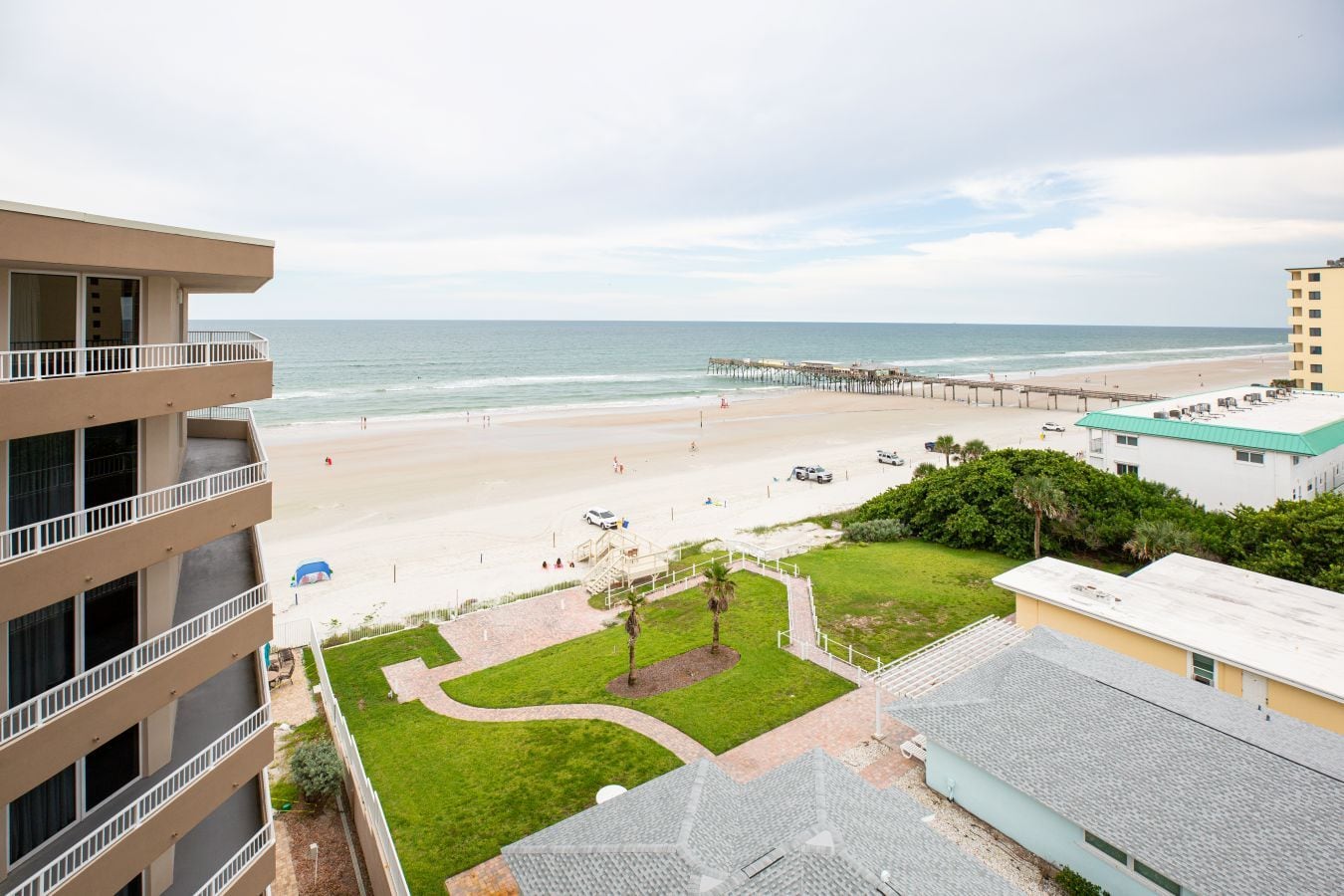 A beachfront hotel with a view of the ocean, a pier, and a parking area.