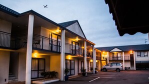 Ein Motel mit mehreren Balkonen, einem Parkplatz und einem davor stehenden Auto.