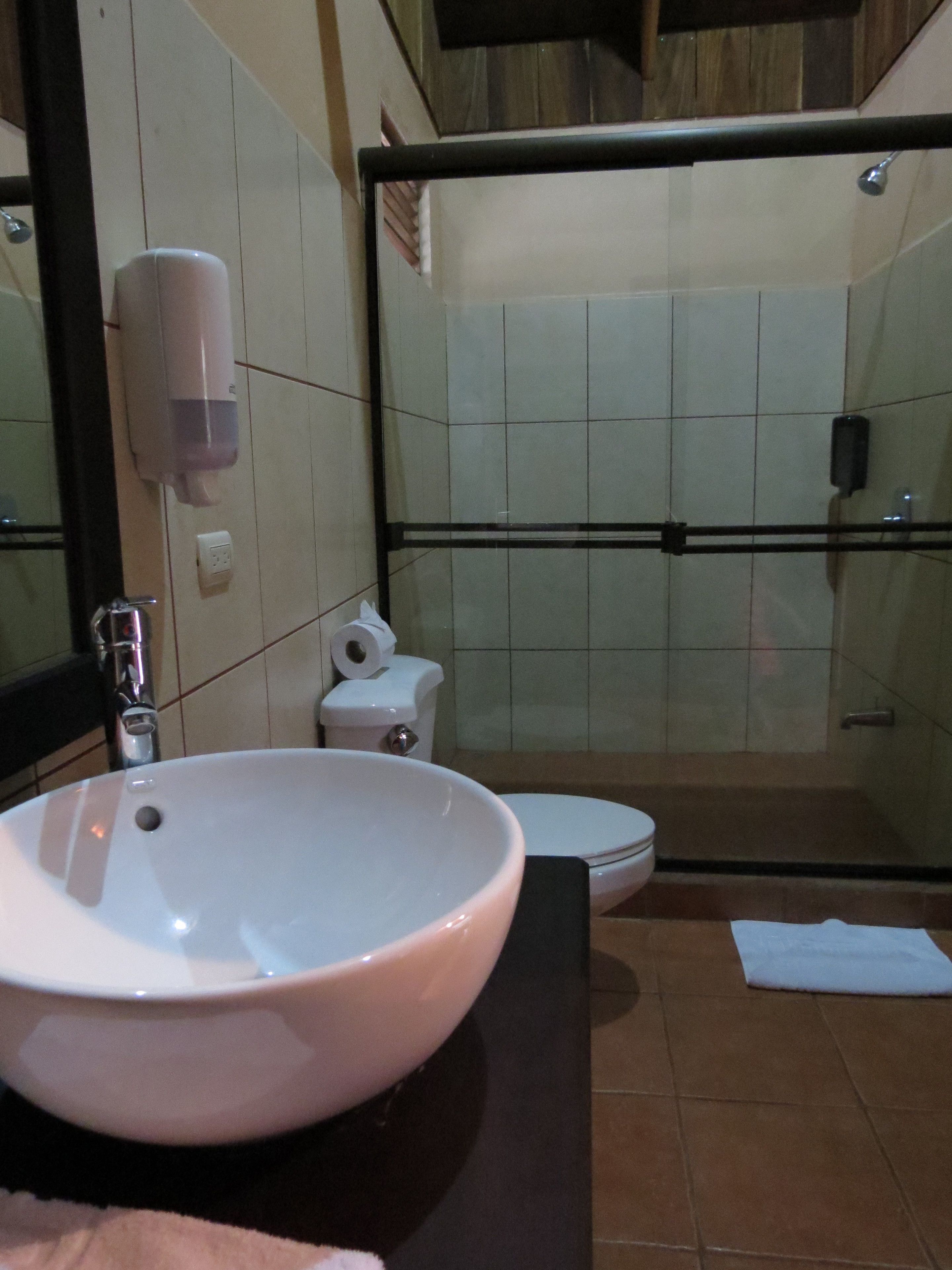 A bathroom with a white sink, toilet, and glass-enclosed shower.