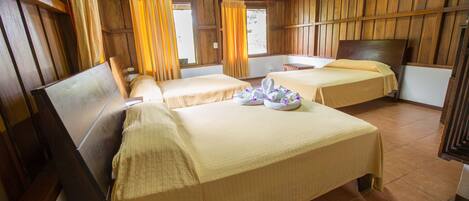 A wooden cabin with two single beds, a wooden ceiling, and a rustic interior.