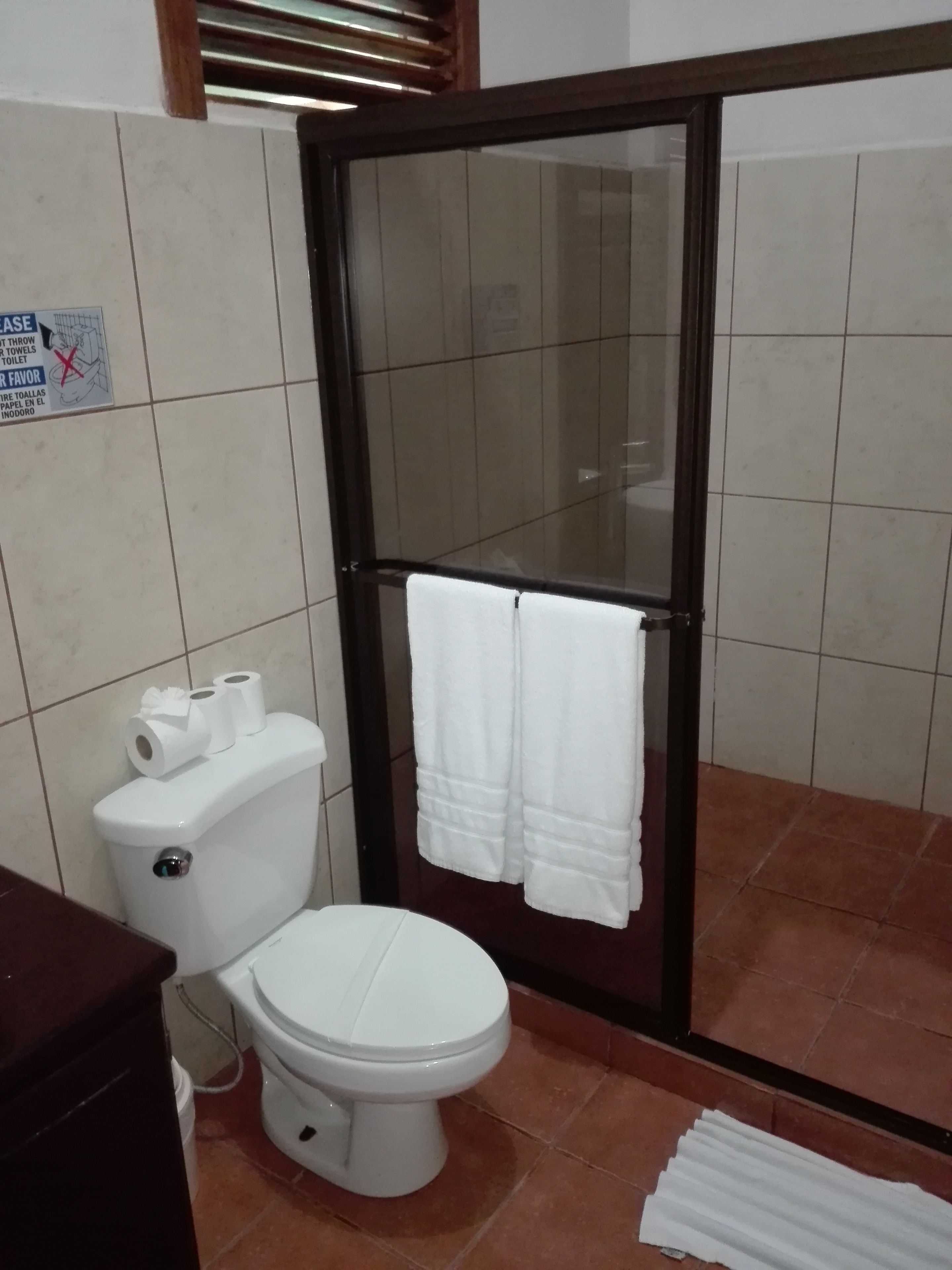 A bathroom with a toilet, a glass shower enclosure, and a tiled floor.