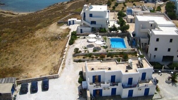 A coastal hotel with a swimming pool, multiple buildings, and a parking area. - Piliouris Studios (Paros)