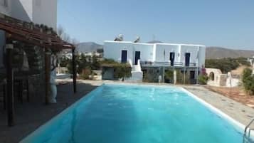 Una piscina al aire libre, sombrillas, sillones reclinables de piscina