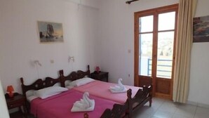 A bedroom with two wooden beds, a pink bedspread, and a swan-shaped pillow. - Piliouris Studios (Paros)