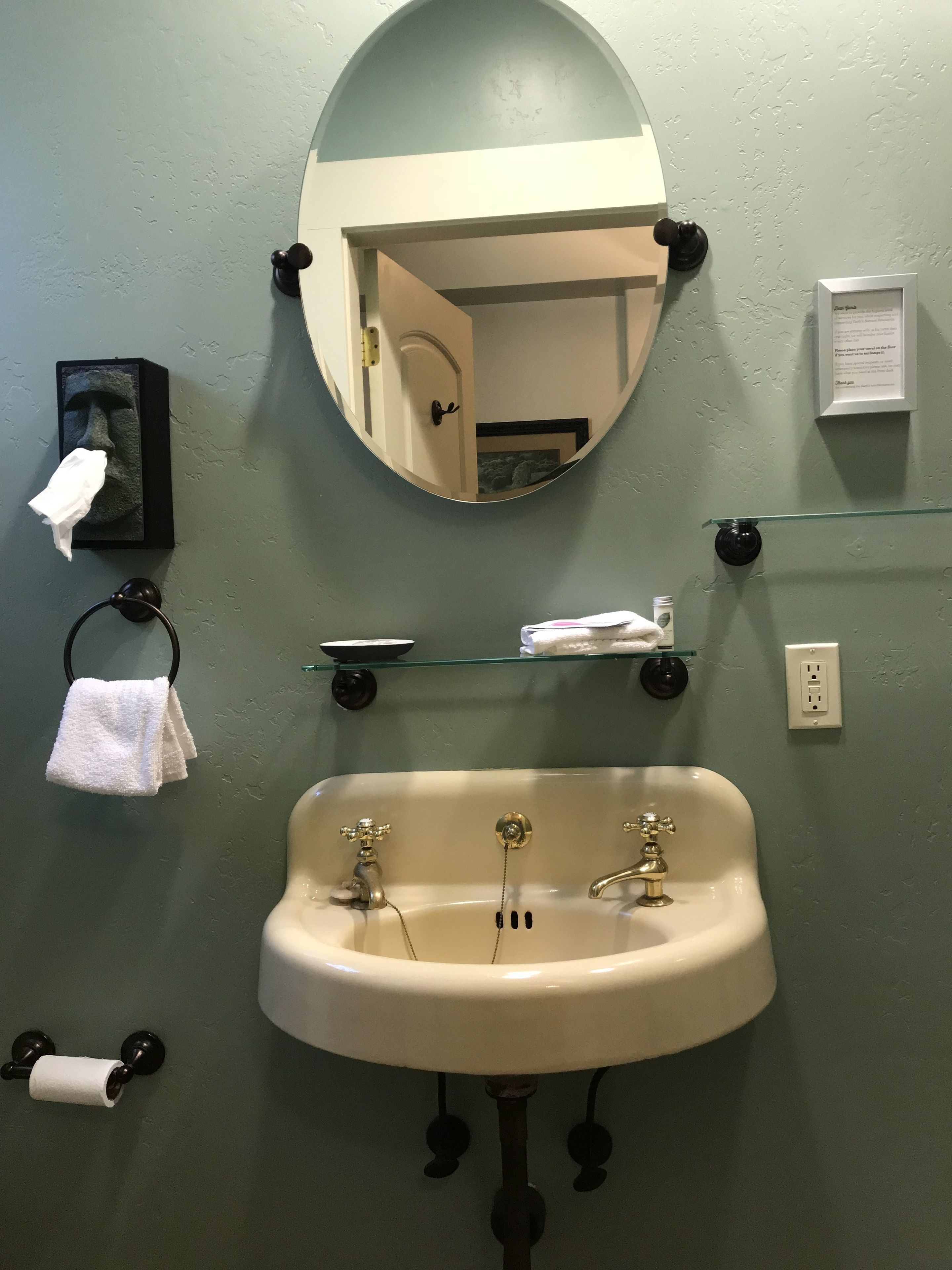 A bathroom with a sink, mirror, towel rack, and a small shelf with toiletries.
