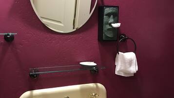 Un bagno con lavandino bianco, uno specchio, portasciugamani e porta carta igienica.