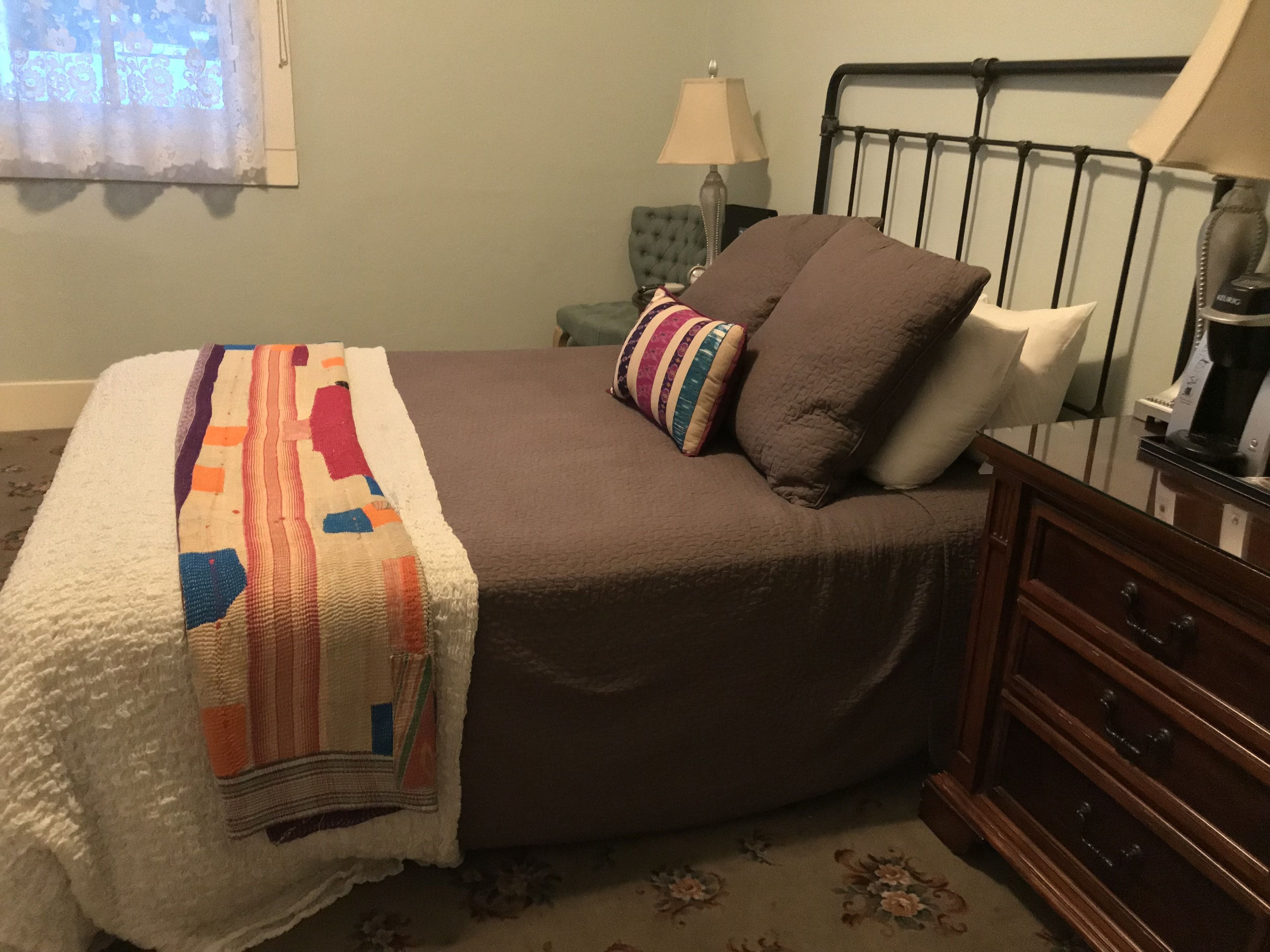 Un dormitorio con cama, mesita de noche, lámpara y cómoda.
