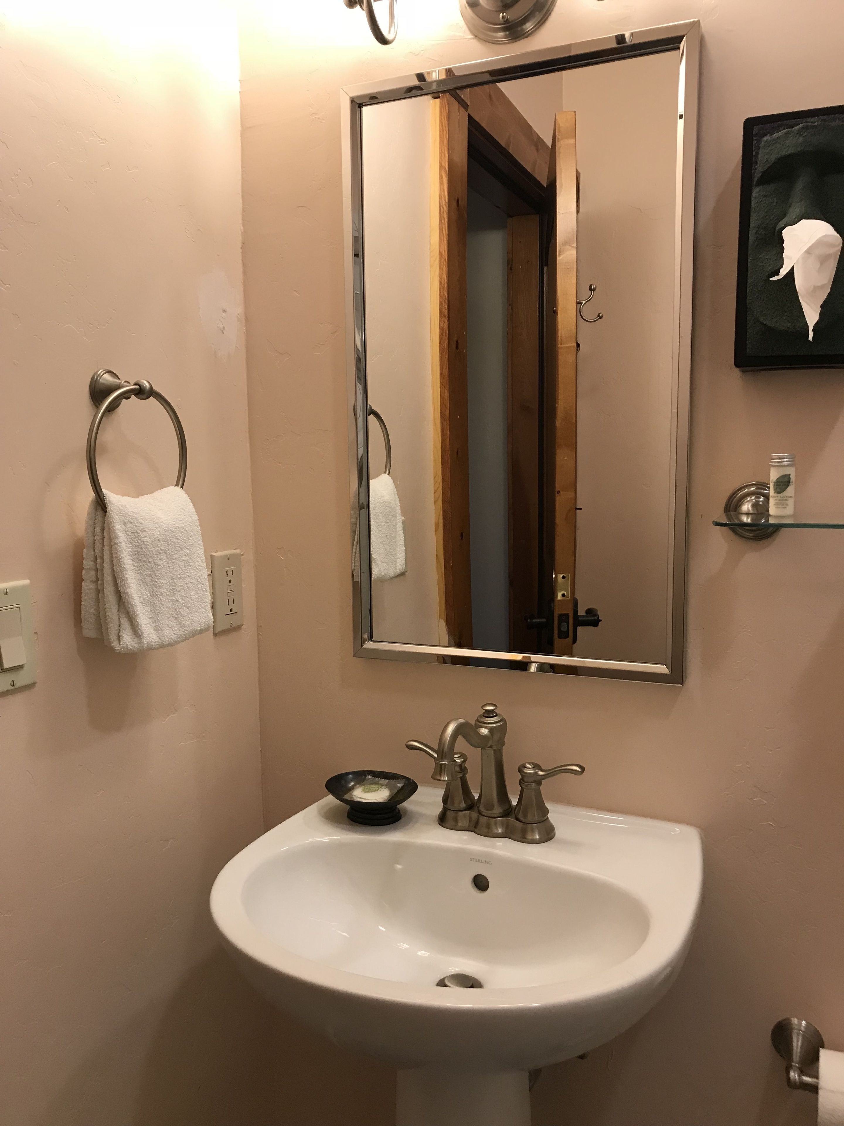 A bathroom with a white sink, a mirror, and a towel rack.