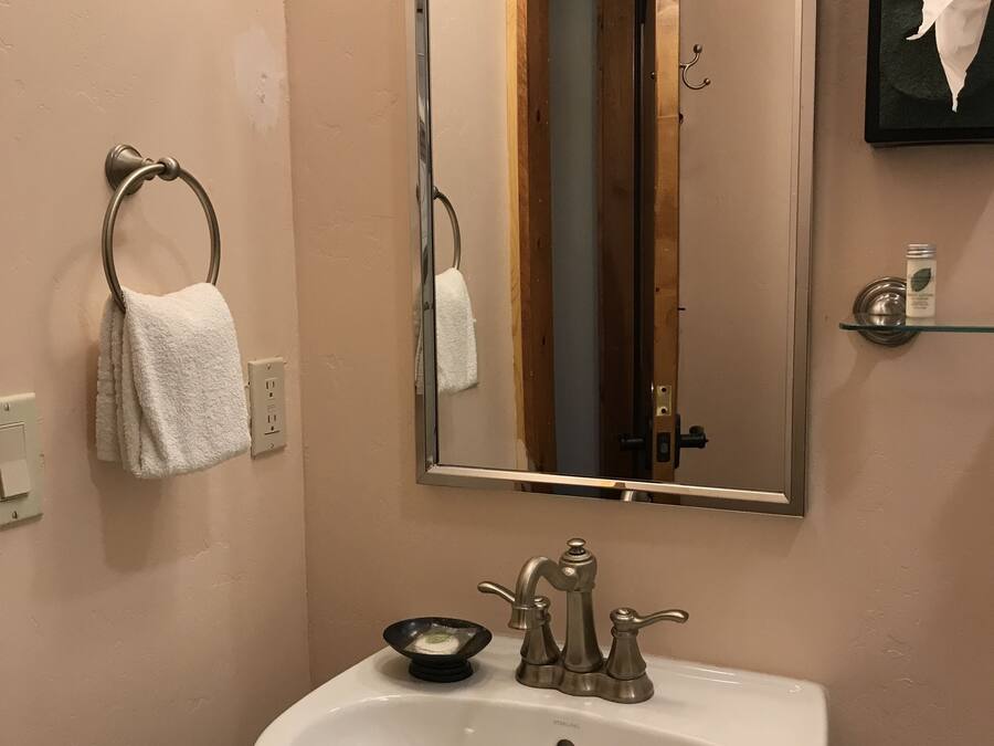 A bathroom with a white sink, a mirror, and a towel rack.