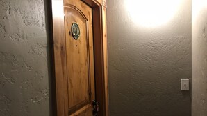 A wooden door with a number plate, a textured wall, and a light switch.