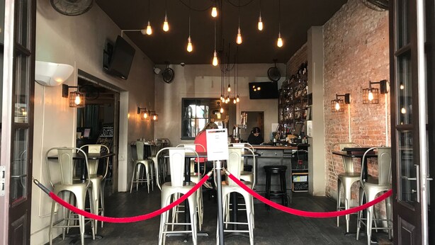 An interior of a restaurant with a bar area, multiple tables, and chairs.